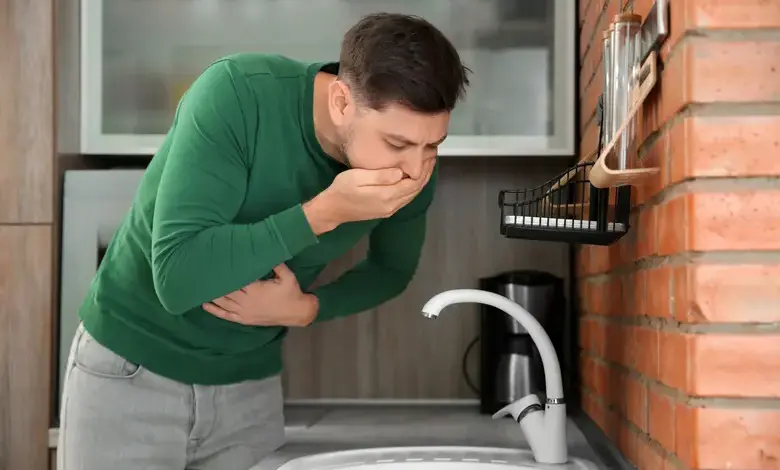 Muž se cítí nemocný v kuchyni u dřezu.
