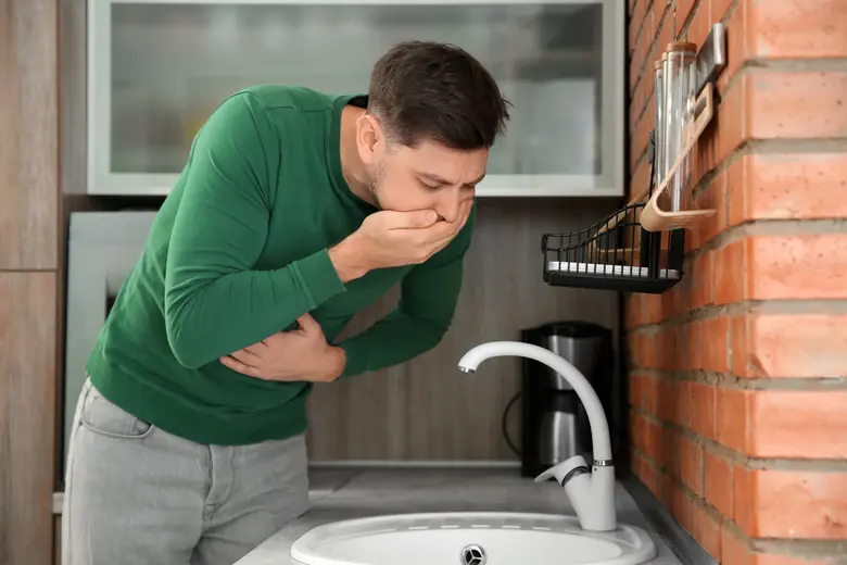 Muž se cítí nemocný v kuchyni u dřezu.