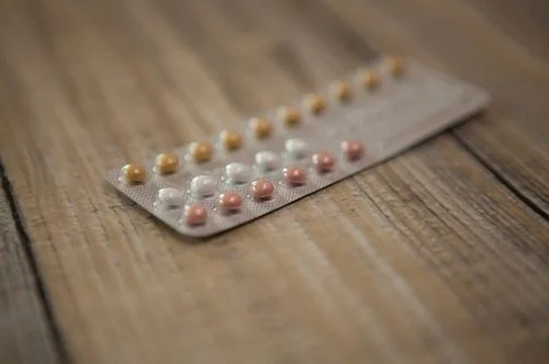 Blister s tabletkami hormonální antikoncepce na dřevě.