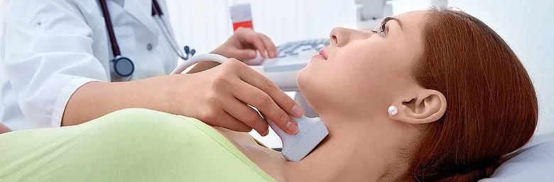 Lékař provádí ultrazvukové vyšetření štítné žlázy pacientce.