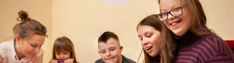Skupina lidí se usmívá při společné činnosti v interiéru.