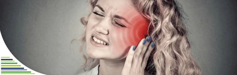 Žena s bolestí ucha drží ruku k bolavému uchu.