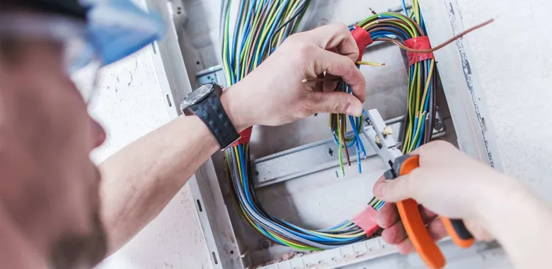 Elektrikář propojuje vodiče v rozvaděči při instalaci.