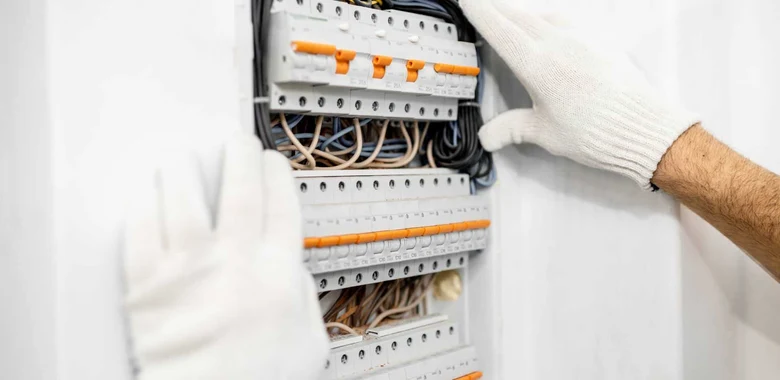 Elektrikář upravuje rozvaděč s viditelným kabelováním.