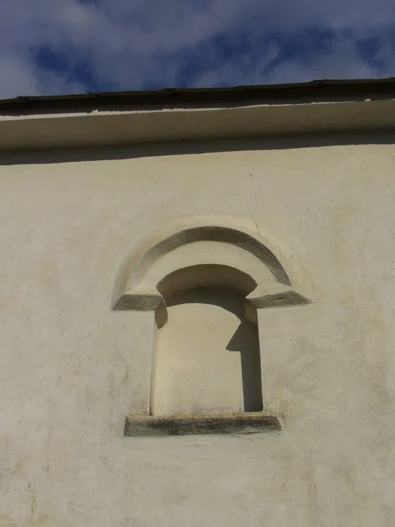 Detail omítky ze vápna na fasádě budovy s obloukovým výklenkem.