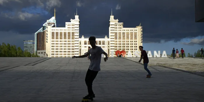 Jezdci na skateboardu před velkými budovami v hlavním městě Kazachstánu