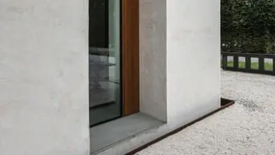 Bílá vápenná omítka na exteriéru domu s oknem v pozadí.