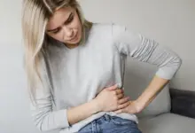 Žena drží břicho v bolesti kvůli křečím.