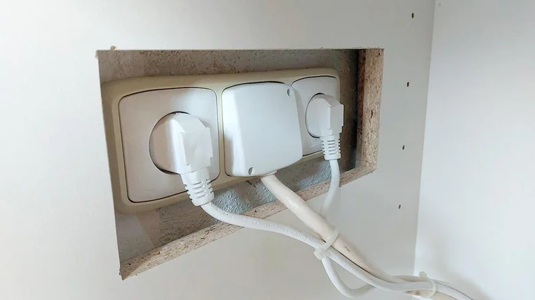 Bílá elektrická zásuvka s nabíječkami v zdi pro elektroinstalaci.